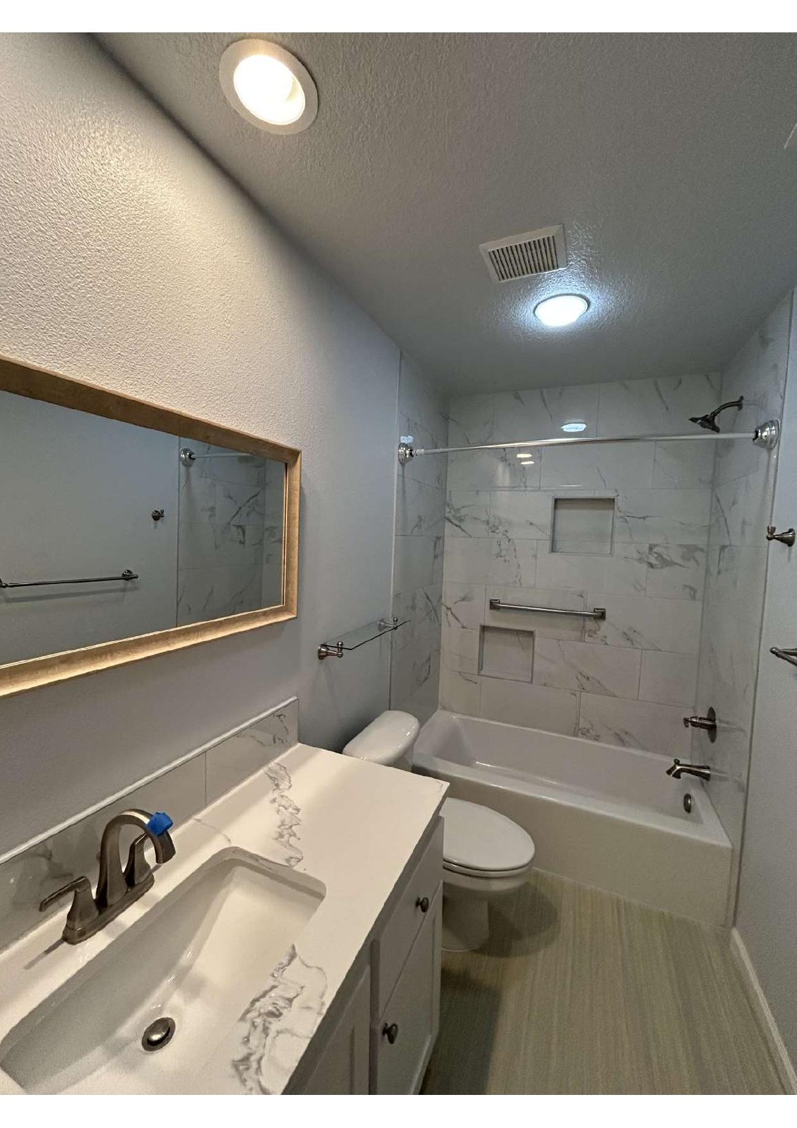 Renovated bathroom with vanity, bathtub, and tiled shower walls