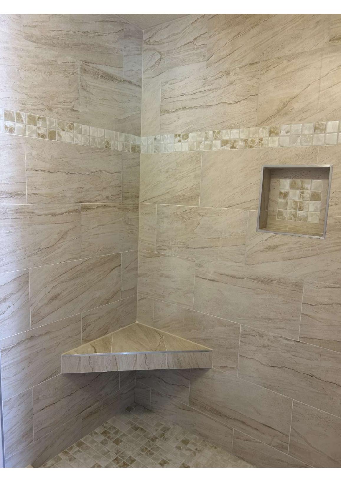 Custom tiled shower corner with built-in bench and recessed niche by VF Remodeling