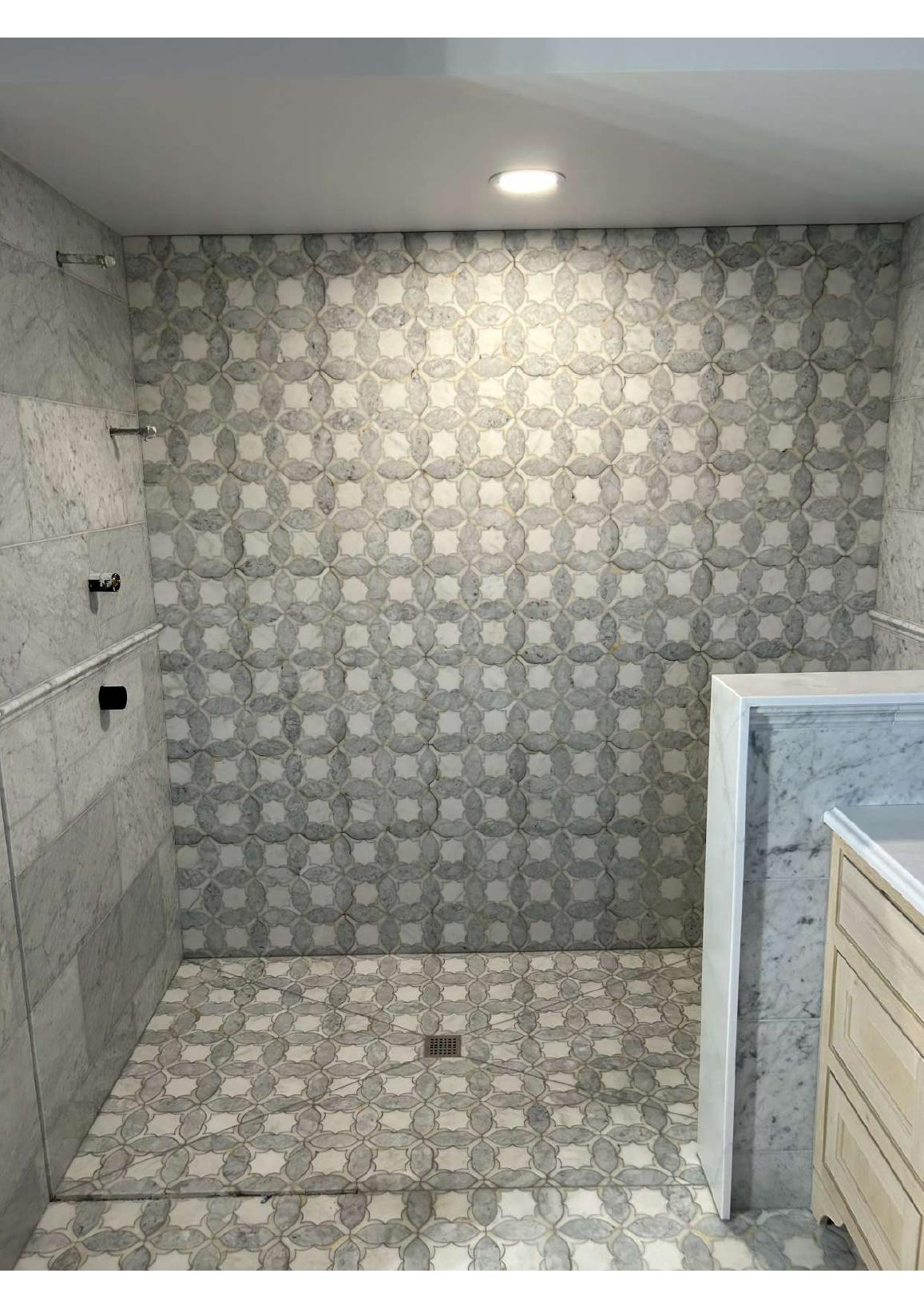 Custom shower with patterned marble tile and built-in vanity