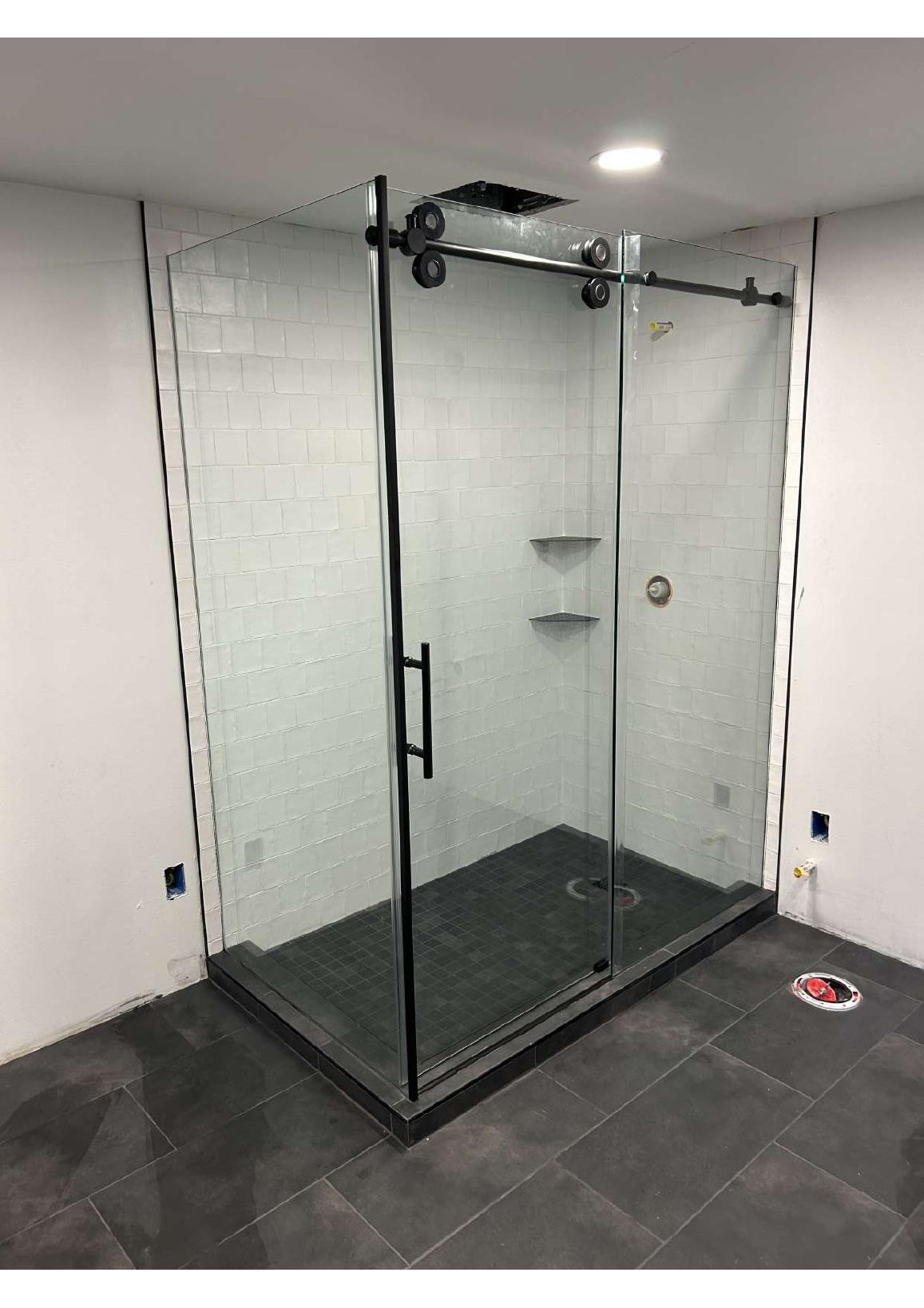 Glass shower enclosure with black hardware and white subway tile